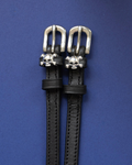Black leather ManeJane spur straps with silver skull and crossbones charms on navy blue