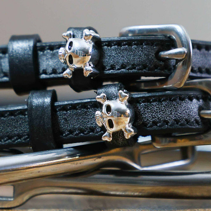 Close-up of silver skull and crossbones charms on black leather spur strap keepers