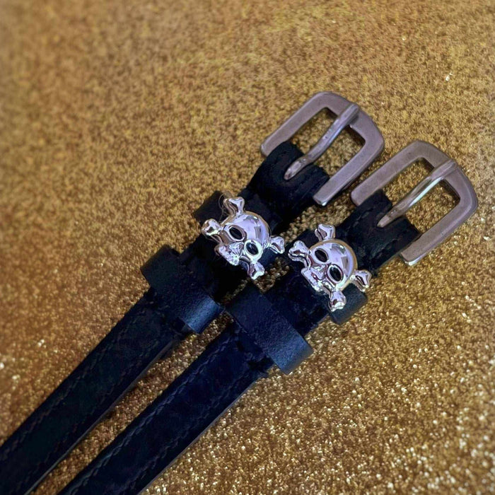 Black leather skull and crossbones ManeJane spur straps on a gold glitter background