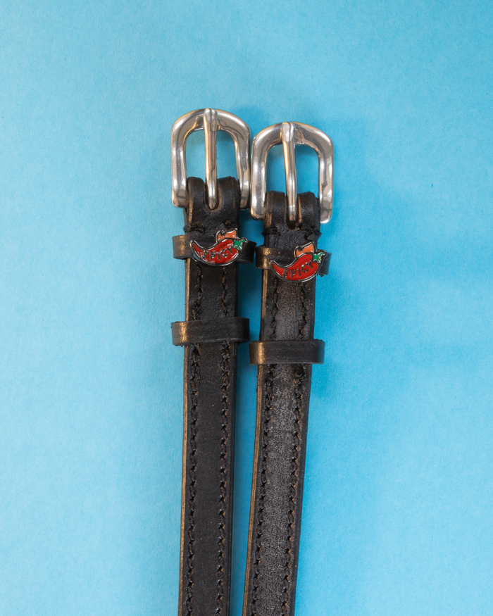 Black leather chili pepper spur straps with silver buckles on a light blue background