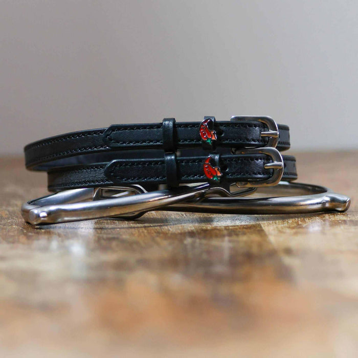 Coiled black leather spicy pepper spur straps resting on a silver spur, red chili charms