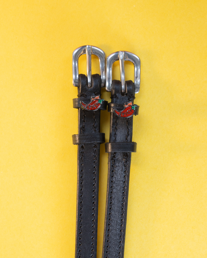 ManeJane spicy pepper spur straps with red chili charms flat on a yellow background
