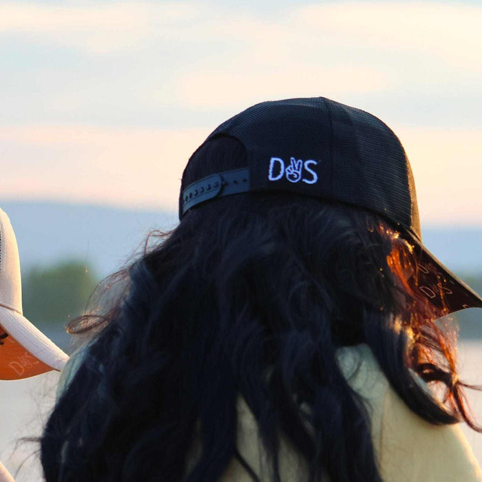Stall Rest Equestrian Bundle black trucker hat worn by person with long hair outdoors at sunset