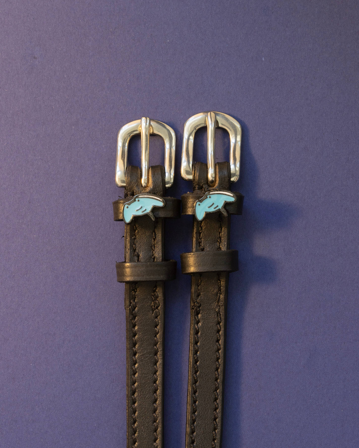 Black leather stingray spur straps with blue stingray charms on an indigo background, ManeJane