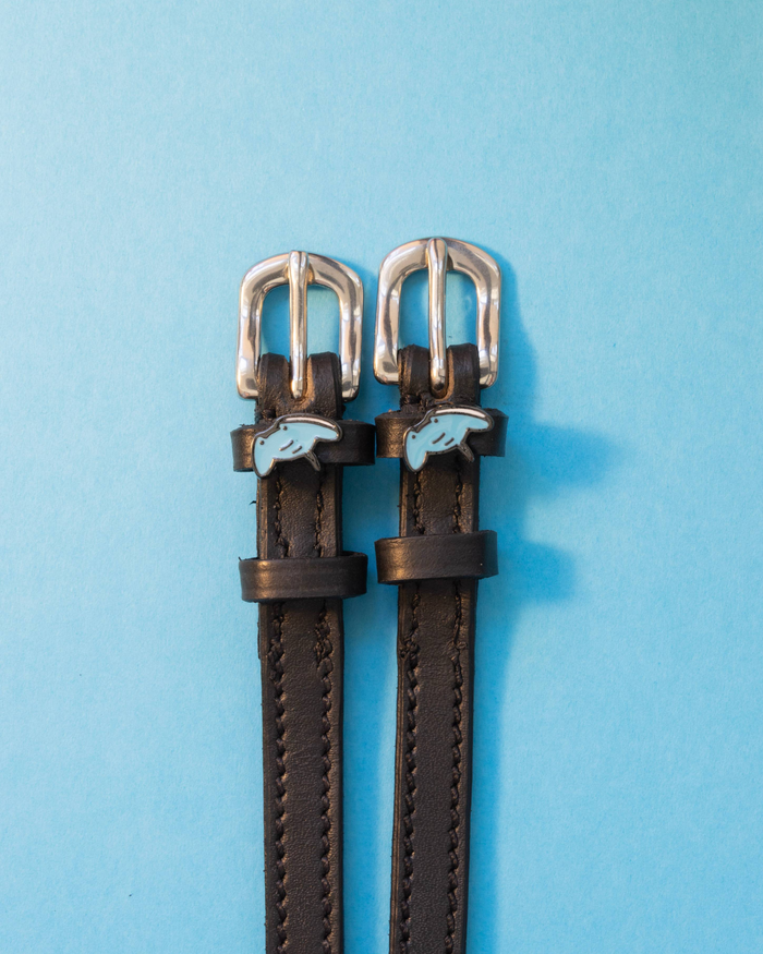ManeJane stingray spur straps with pale blue ray charms on a light blue background
