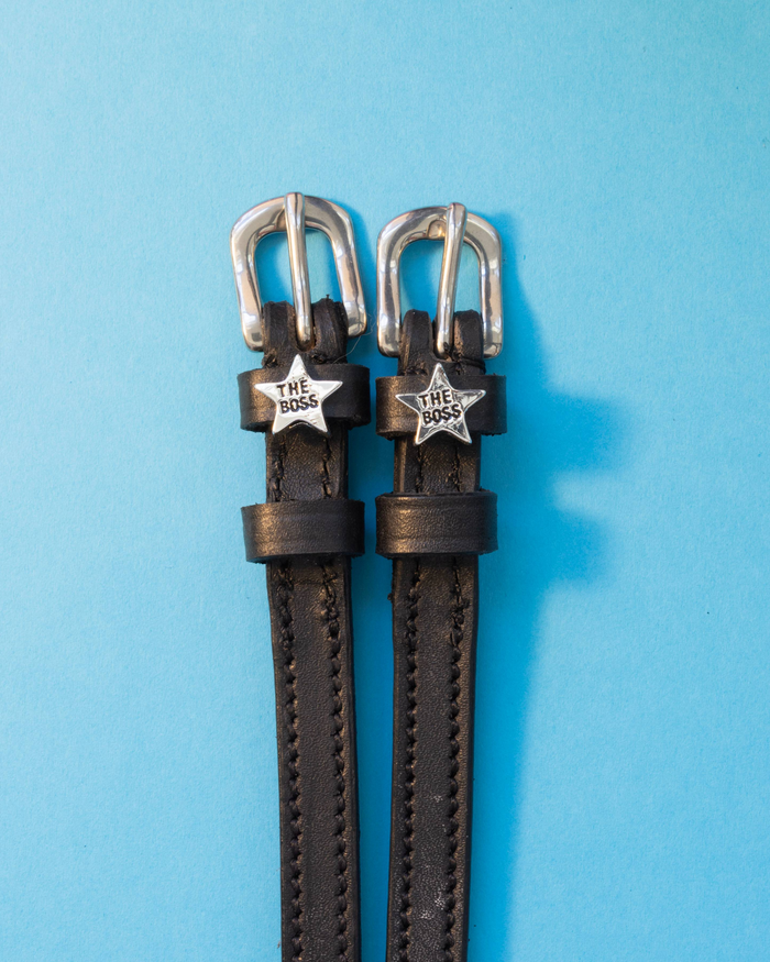 Black leather Boss star spur straps with silver buckles on a light blue background