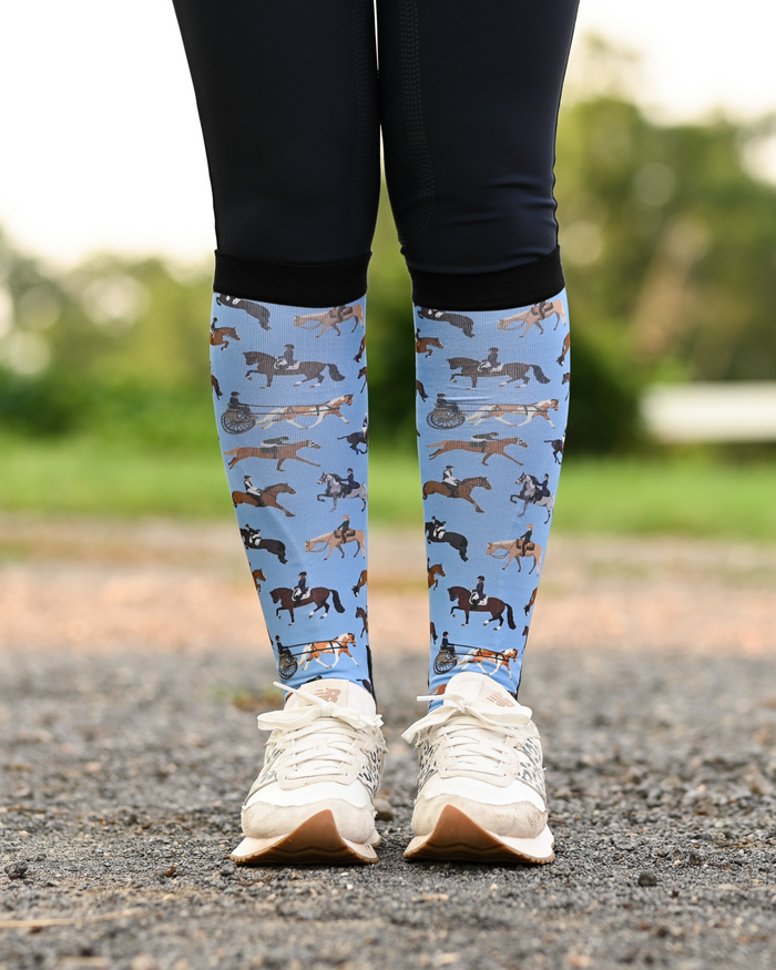 The Pony Island Horse Sports equestrian boot socks worn at the barn, light blue with riders mounted across every discipline