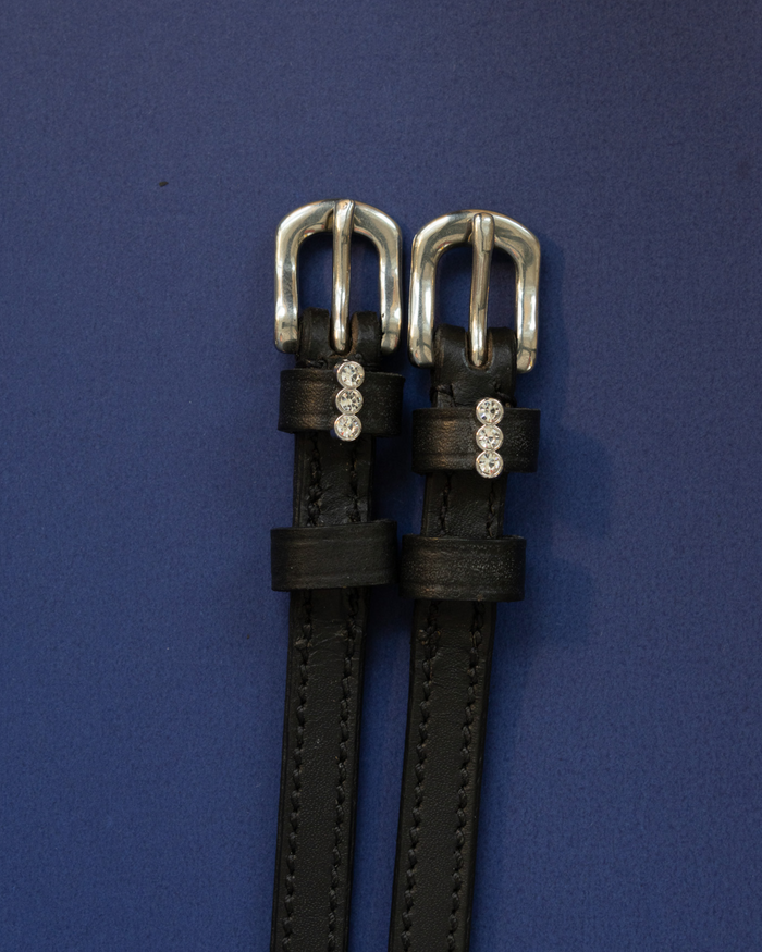 Black leather ManeJane spur straps with three-crystal charms and silver buckles on navy