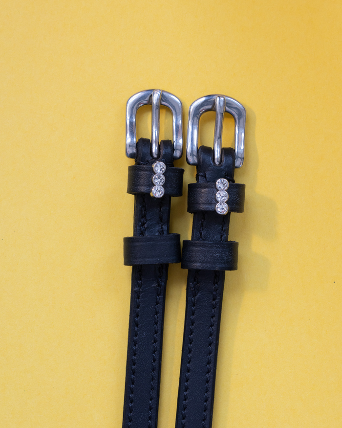 ManeJane three-crystal charm spur straps on black leather against golden yellow