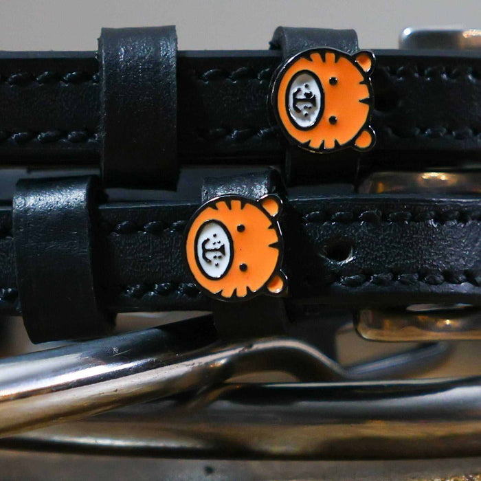 Close-up of orange tiger-face charms on black leather spur strap keepers