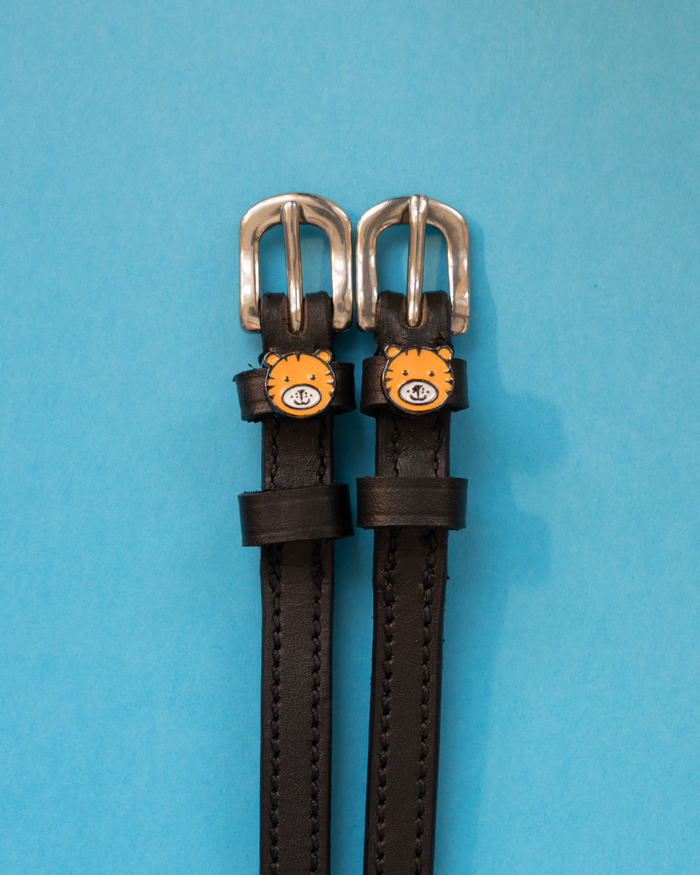 Pair of black leather tiger spur straps with silver buckles on a light blue background