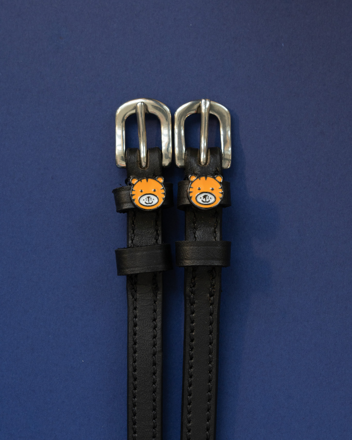 ManeJane tiger spur straps with silver buckles laid flat on navy blue