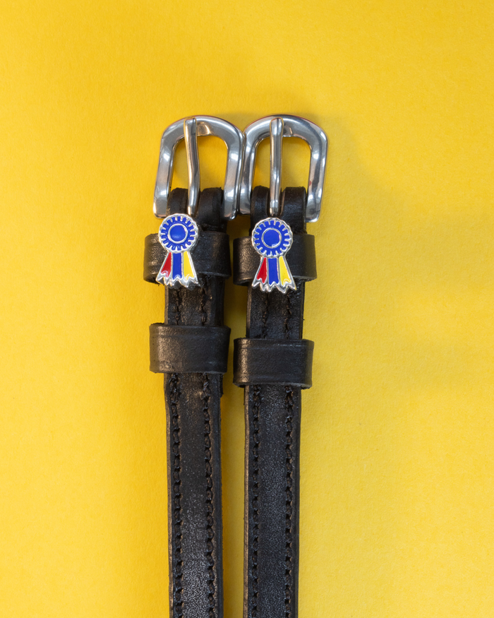 Black leather spur straps with blue and tri-color ribbon rosette charms on yellow
