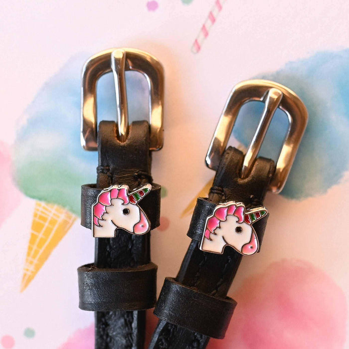 Gold buckle ends of unicorn spur straps against a pastel ice-cream watercolor background