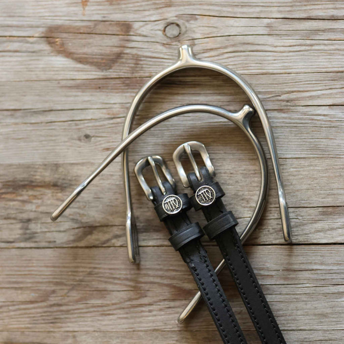 Black leather Virgo zodiac spur straps arranged with a silver spur on rustic wood