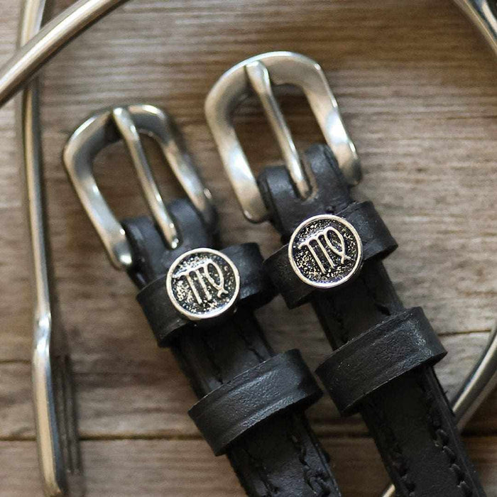 Macro of Virgo zodiac charms and silver buckles on black leather spur straps and spur
