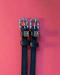 Black leather ManeJane spur straps with waffle-and-butter charms on red