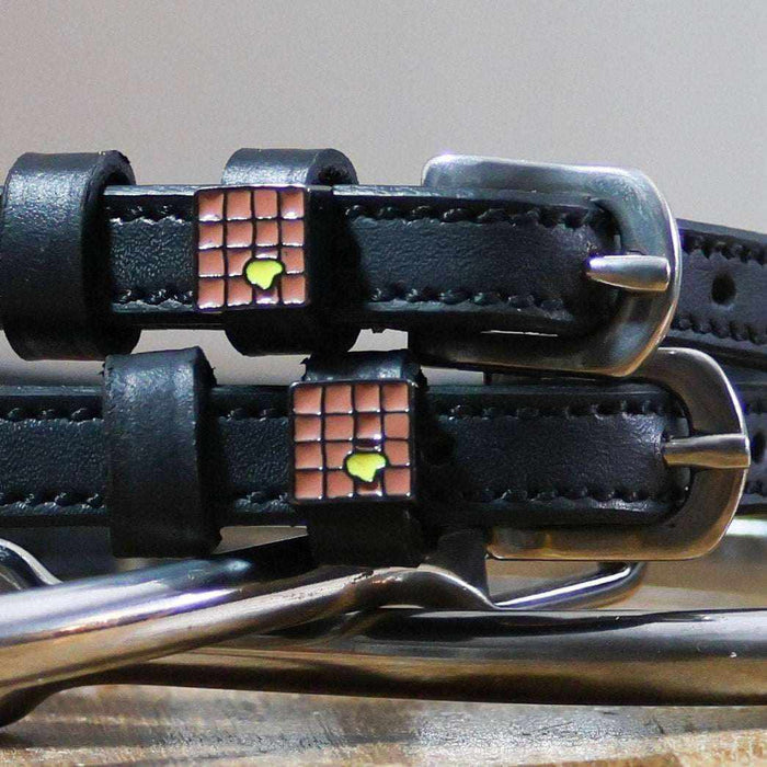 Close-up of enamel waffle charms with a pat of butter on black spur straps