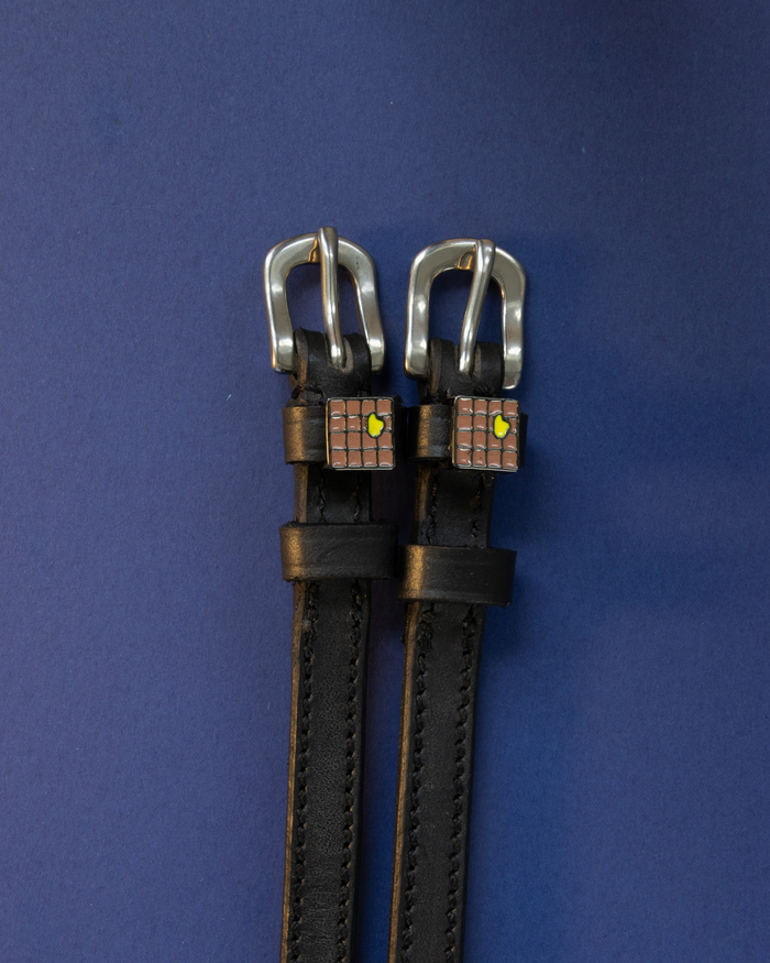 Pair of waffle-charm ManeJane spur straps flat on a navy background