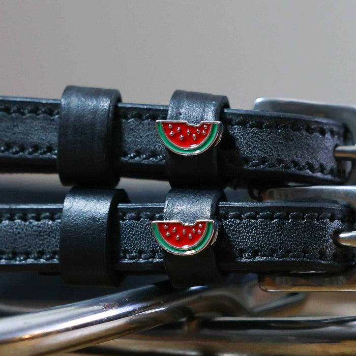 Close-up of enamel watermelon slice charms on black leather ManeJane spur strap keepers