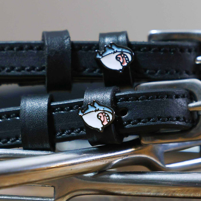 Close-up of a blue-and-white shark head charm on a black leather ManeJane spur strap keeper