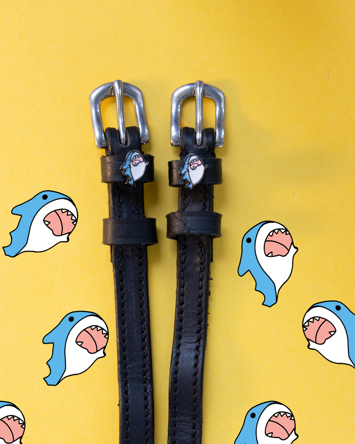 Black leather shark spur straps on yellow with scattered cartoon shark illustrations